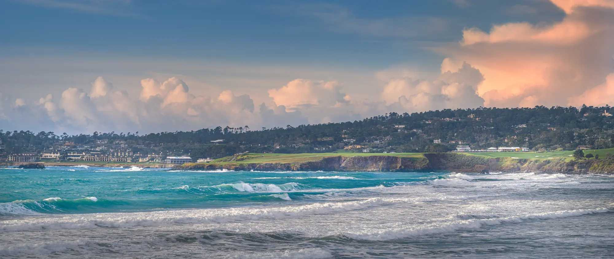 The Pebble Beach shoreline and golf links on the headland, seen across Carmel Bay