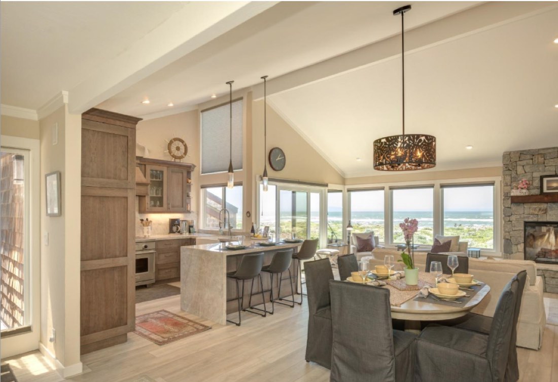 Open-plan living and dining room at 274 Monterey Dunes Way, looking through windows to the dunes and ocean beyond